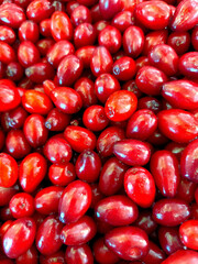 Heap of ripe dogwood berries with rich red color. Natural texture background of fresh cornelian cherrie