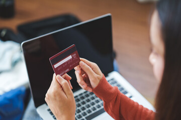 A young woman is holding a credit card to conduct financial transactions over the internet.