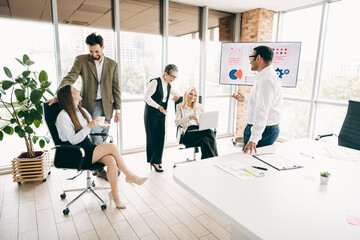 Fototapeta premium Diverse team collaborating in a modern office space with technology displays and discussing project strategies.