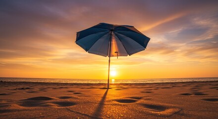 A serene beach scene at sunset. A blue & white parasol stands tall, casting a long shadow on the sandy foreground as the sun sets