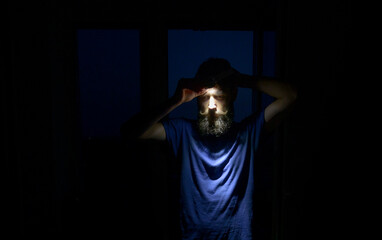 Bearded man adjusting headlamp at night, camping gear and survival equipment for hiking, trekking and outdoor adventure safety © XArt