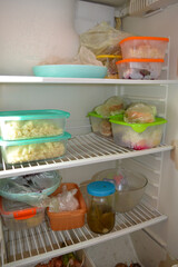 Open refrigerator with food storage in plastic containers and jars. Concept of meal prep, homemade food, and healthy lifestyle.