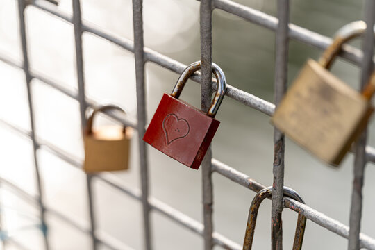Locks symbolizing love attached to a metal fence near a river in a picturesque setting during the evening