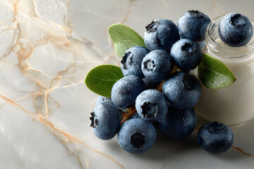 Blueberries with leaves on a marble surface.