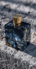 Dark, rectangular perfume bottle with gold accents, resting on a stone surface