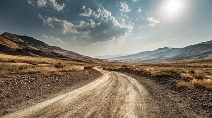 Winding dirt road leads into the distance through a dry, mountainous landscape under a partly cloudy sky, symbolizing exploration and journeys.