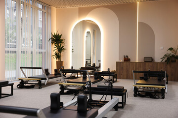 Many reformer machines in studio. Pilates equipment