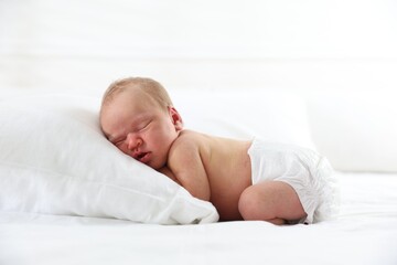 Cute newborn baby sleeping on bed indoors