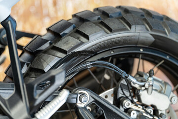 Motorcycle tire close-up showcasing its rugged tread and intricate brake system in a garage setting