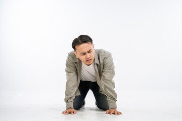 A young man is kneeling on the floor, showing signs of physical discomfort and struggle
