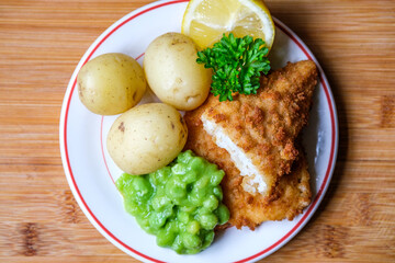 Breaded Cod Fish Fillet With Boiled New Potatoes And Mushy Peas
