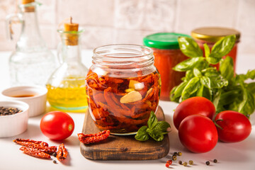 Dried organic tomatoes preservation with herbs and olive oil in jar.