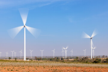 Field of wind turbines with motion blur on their blade using long exposure during sunny day and blue sky