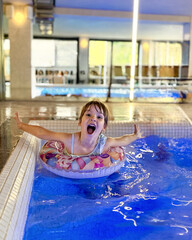 A girl is swimming in a pool on an inflatable ring.