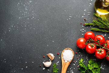 Food background with fresh vegetables, herbs and spices on black.