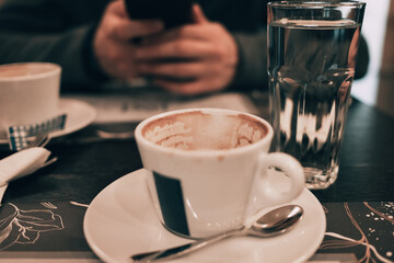A close-up of two empty coffee cups on a saucer with spoon, served at a cozy cafe table. Date in cafeteria