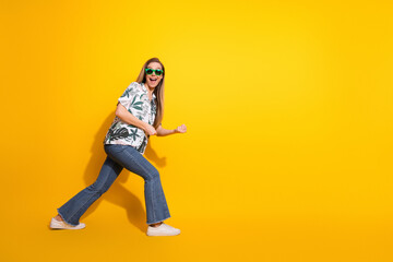 Beautiful young woman in casual tropical print shirt posing confidently on bright yellow background with cheerful smile
