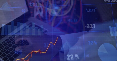 Business executive in suit entering data on laptop at office desk, with financial chart overlays