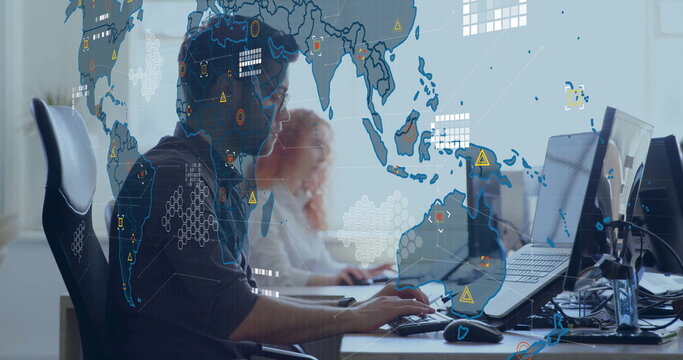 Monitoring two IT analysts in shirts scanning alerts in office, with monitors world map overlay