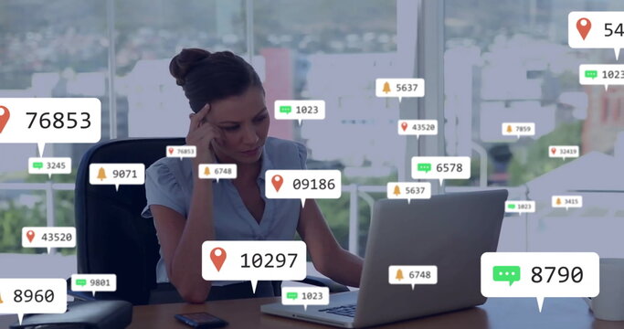 Analyzing businesswoman reviewing social media metrics at office desk, with laptop data bubbles