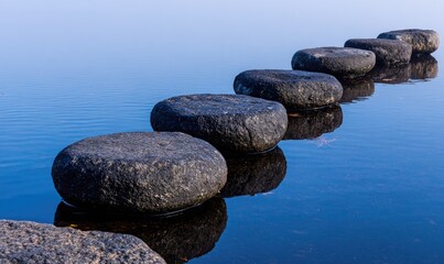 Smooth, dark stones form a pathway across calm water