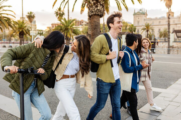 Fototapeta premium Happy millennial generation students walking and talking together at city street