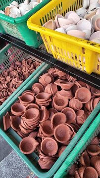 Stacks of traditional unglazed clay oil lamps, also known as diyas, arranged in green plastic baskets for sale at a market.