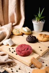 Assorted gourmet cookies on rustic wooden boards—red velvet, chocolate, sprinkle, marshmallow and speculoos—styled in a dark studio for menus, ads, packaging, and social content.