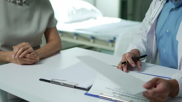 Healthcare provider explaining medical treatment, reviewing documents with patient in clinical consultation room