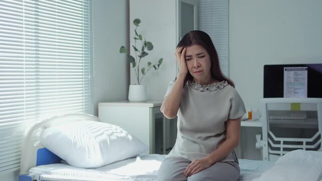 Patient seated on hospital bed, experiencing severe headache, displaying pain and emotional strain with visible physical discomfort