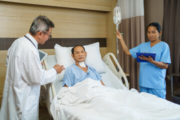 Obraz premium Doctor and nurse visiting elderly man after tracheostomy surgery in recovery room.