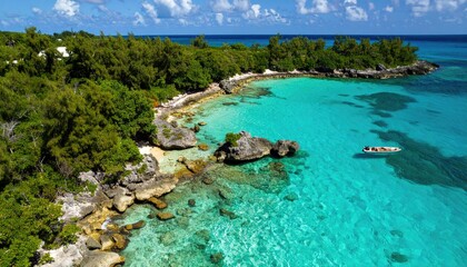 Tropical coastline with turquoise water. Aerial view of a secluded beach fringed with lush greenery and rocky outcrops. A small boat floats on the crystal-clear water