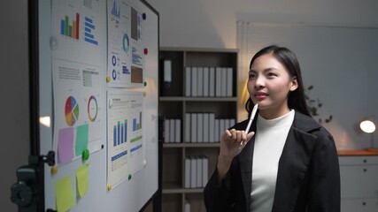 Professional asian businesswoman analyzing marketing data, presenting strategic insights with confidence during corporate meeting in modern office environment - Powered by Adobe