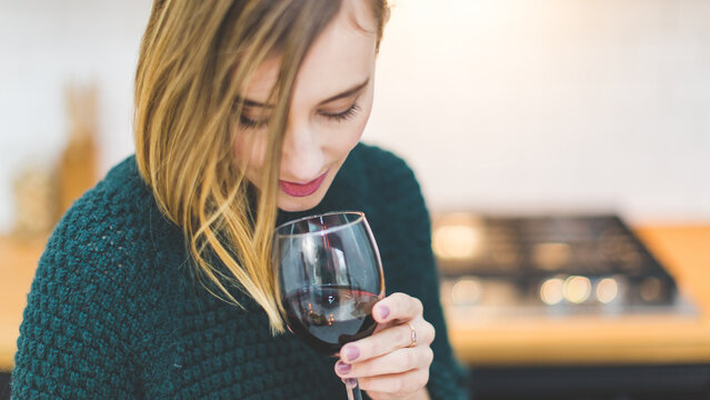 Close Up Moody Portrait of Woman Smelling Red Wine in Glassware