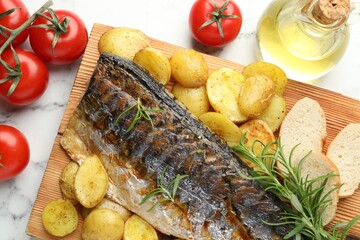 Tasty roasted mackerel with spices and vegetables on white marble table, flat lay. Homemade seafood dish