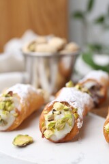 Delicious cannoli with ricotta cheese, pistachios and powdered sugar on table indoors, closeup