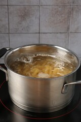 Fresh pasta boiling in pot with water on electric stove, closeup