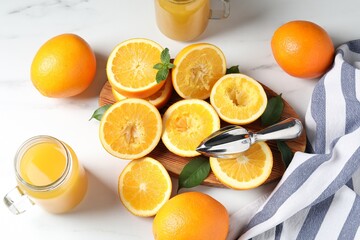 Freshly squeezed orange juice, fruits, juicer and towel on white table, flat lay
