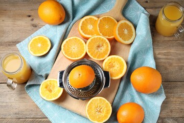 Freshly squeezed orange juice, fruits, juicer and towel on wooden table, flat lay