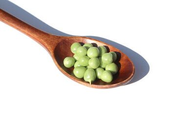 On a white background lies a wooden spoon with fresh green peas.