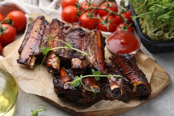 Roasted beef ribs with microgreens, tomatoes and sauce on table, closeup
