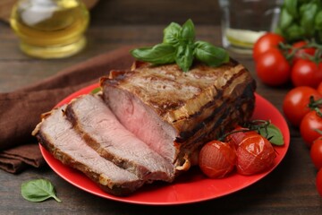 Delicious baked beef meat, tomatoes and basil on wooden table, closeup