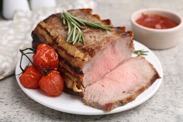 Delicious baked beef meat, tomatoes, rosemary and sauce on grey table, closeup