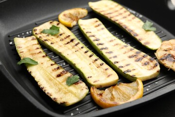 Delicious grilled courgette slices with salt, lemon and parsley in pan, closeup