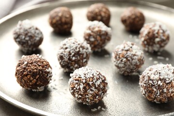 Tasty chocolate candies with nuts and coconut flakes on table, closeup