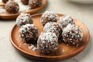 Tasty chocolate candies with nuts and coconut flakes on light table, closeup