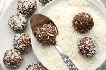 Making tasty chocolate candies with coconut flakes at table, top view