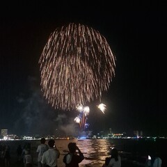 A stunning display of bright white fireworks exploding in the night sky over a body of water. The...