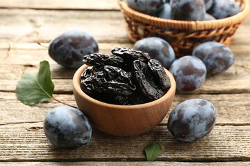 Dried prunes and fresh plums on wooden table, closeup