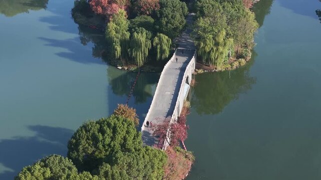 Aerial view of a stone bridge connecting green islands across a tranquil lake with natural scenery
